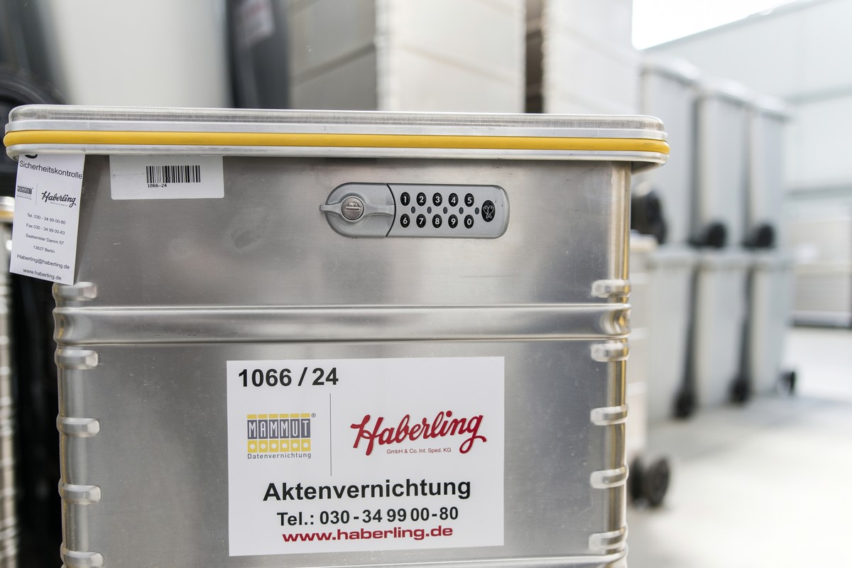 Im Fokus steht ein Metallbehälter mit einem Zahlenschloss, der mit „Haberling“ beschriftet ist. Im Hintergrund ist eine Reihe ähnlicher Behälter verschwommen zu sehen.
